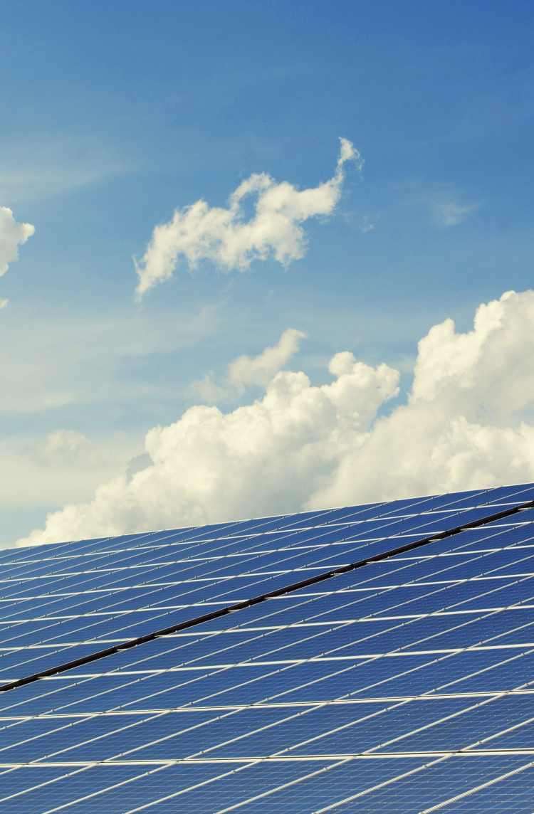 Zonnepanelen op de voorgrond en op de achtergrond wolken op een blauwe lucht