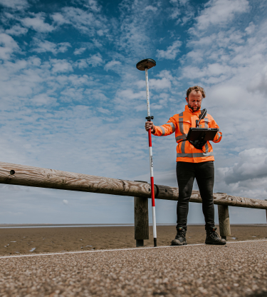 Man in oranje hesje voert een meting uit bij Veerhaven