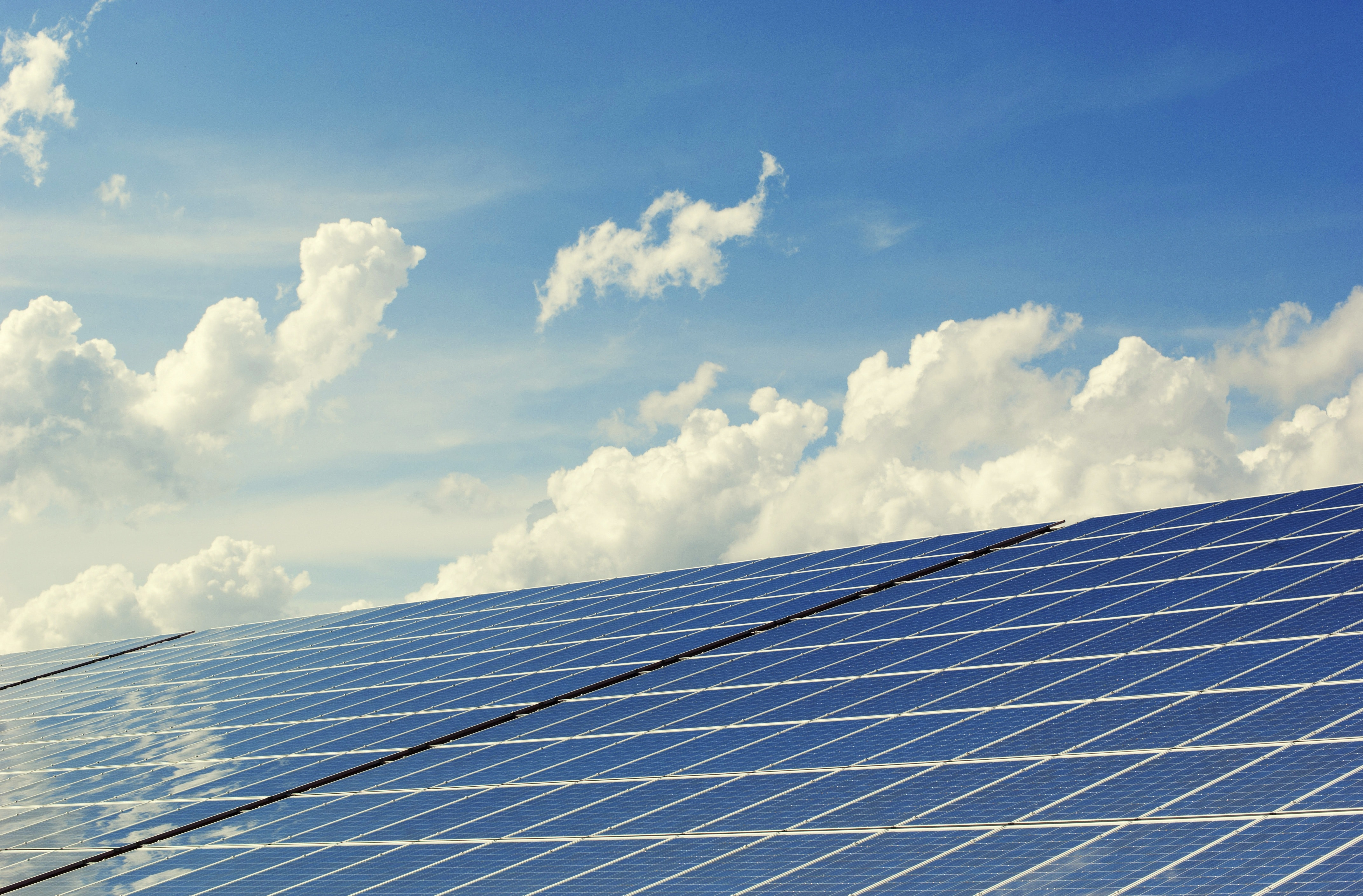 Zonnepanelen op de voorgrond en op de achtergrond wolken op een blauwe lucht